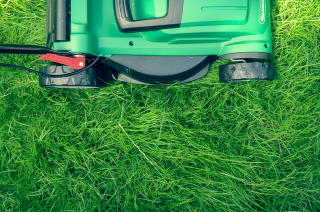 Close-up of a green artificial grass lawn with a lawn mower.