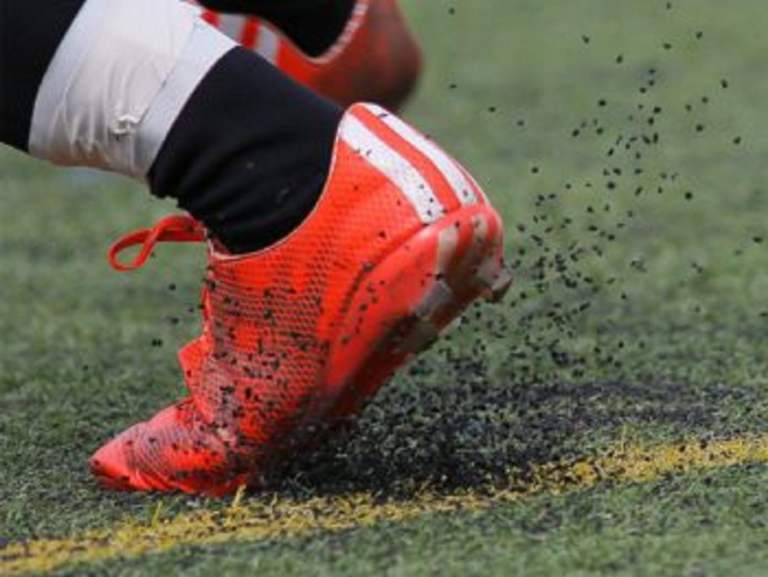 Close-up of a soccer cleat on artificial turf during a game.