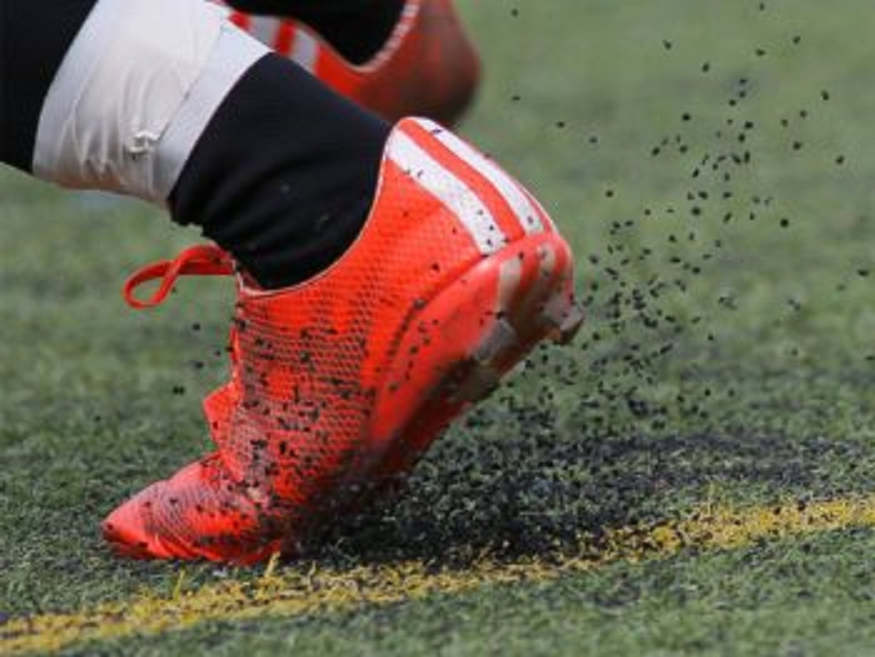 Close-up of a soccer cleat on artificial turf during a game.