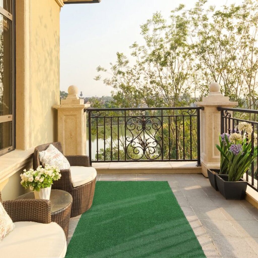 Balcony with artificial grass, outdoor seating, and potted plants in warm sunlight.