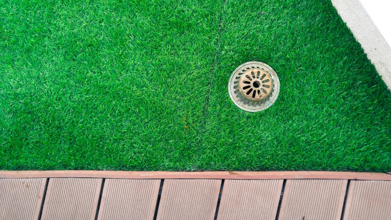 Close-up of synthetic turf with drainage grate in Arizona luxury lawn.
