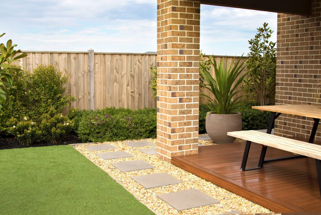 Beautiful backyard with artificial turf, pavers, and a wooden deck.
