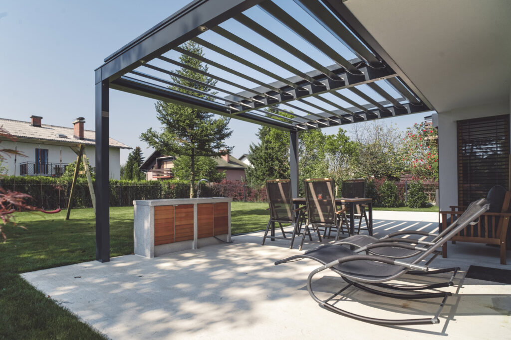 Modern outdoor patio with pergola, lounge chairs, and dining area in a landscaped backyard.