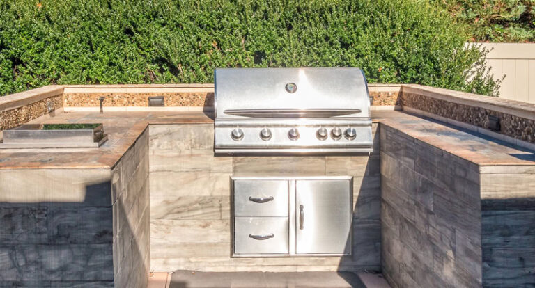 Stainless steel outdoor BBQ grill with storage in backyard.