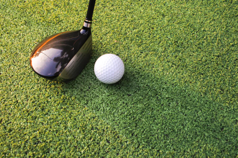 Golf club and ball on synthetic turf for golf practice.