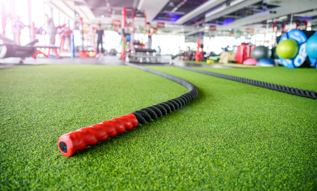 Synthetic grass flooring with battle ropes in a gym setting.