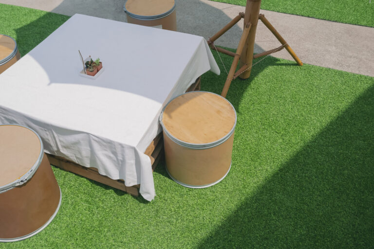 Artificial turf with outdoor furniture and a table in a backyard setting.