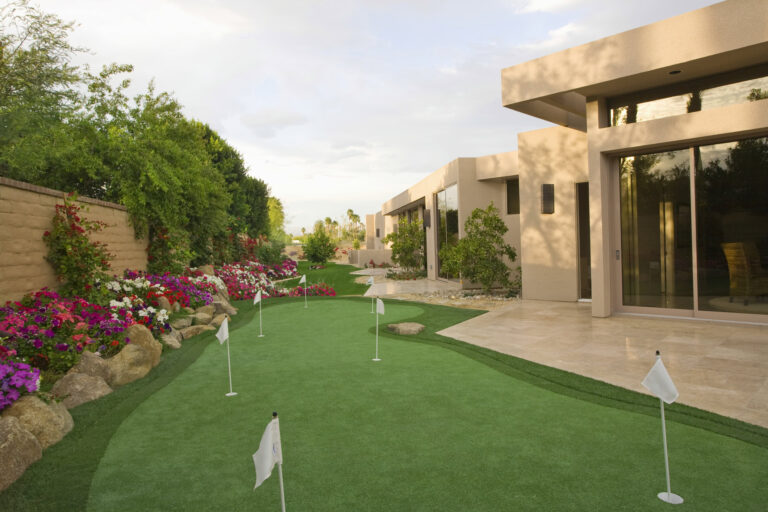 Luxury synthetic grass putting green with flags and landscaping in Arizona.
