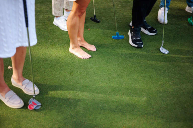 People playing mini golf on a lush green artificial turf putting green.