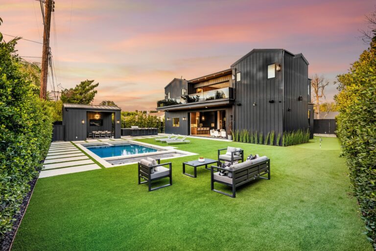 Luxury backyard with pool, modern house, and well-maintained lawn at sunset.