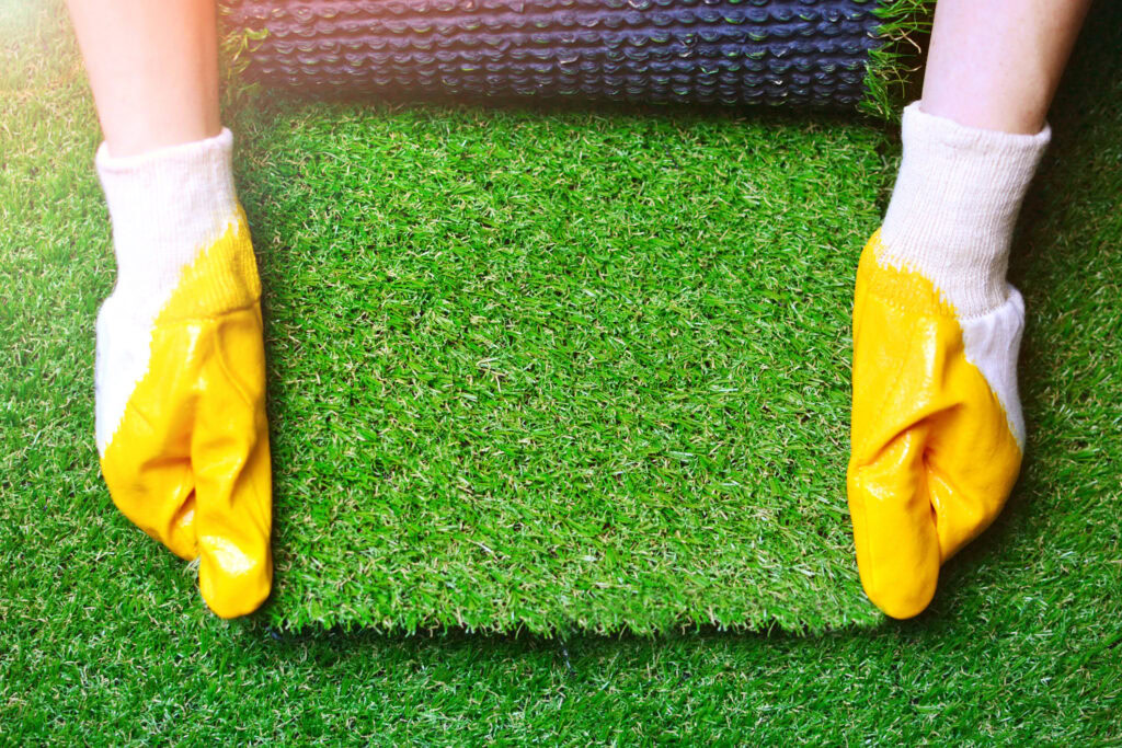 Person installing artificial turf for a putting green with gloves.