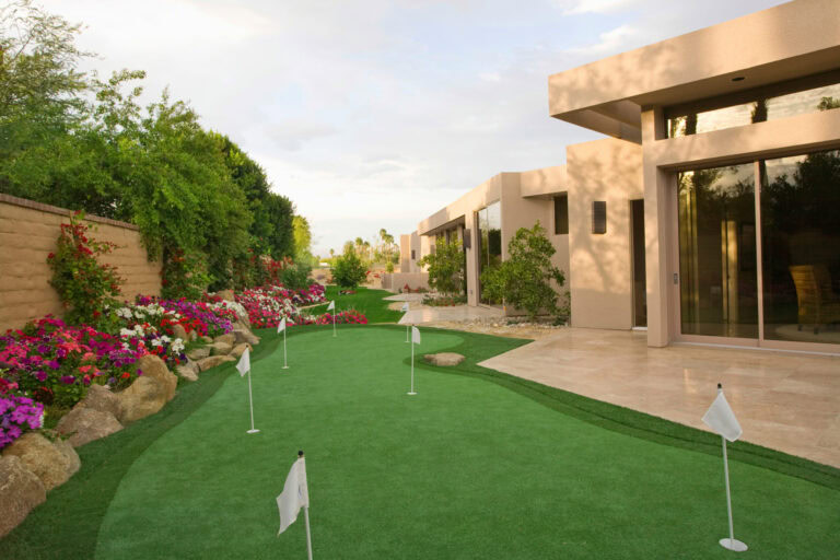 Luxury backyard with artificial turf putting green and modern house design.
