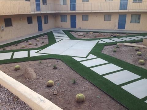 Modern backyard with synthetic grass and concrete pathways for a putting green.