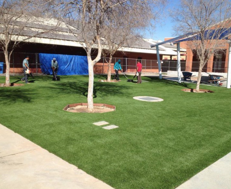 Beautiful artificial turf lawn with trees and people playing golf.