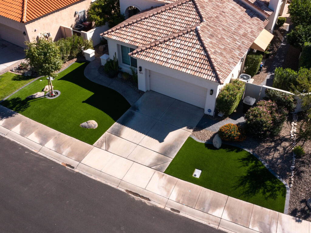 Aerial view of residential front yard with curved artificial turf flanking driveway, stucco home with terracotta tile roof, Scottsdale Arizona