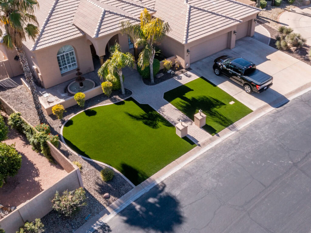Aerial view of luxury residential front yard with artificial turf, palm trees, arched entryway, and paver walkway, Scottsdale Arizona