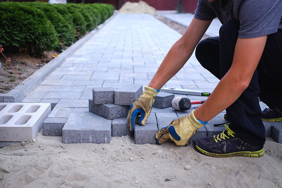 Person laying pavers for a luxury lawn or putting green in Arizona.