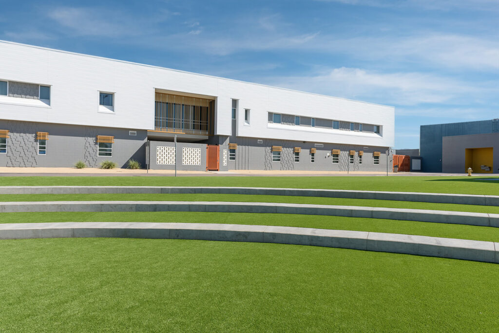 Modern building with lush green artificial turf and tiered landscape.