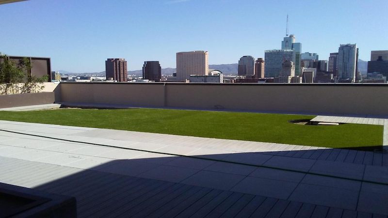 Artificial turf installation on urban rooftop with wide deck area and downtown Phoenix skyline and mountain range views in background