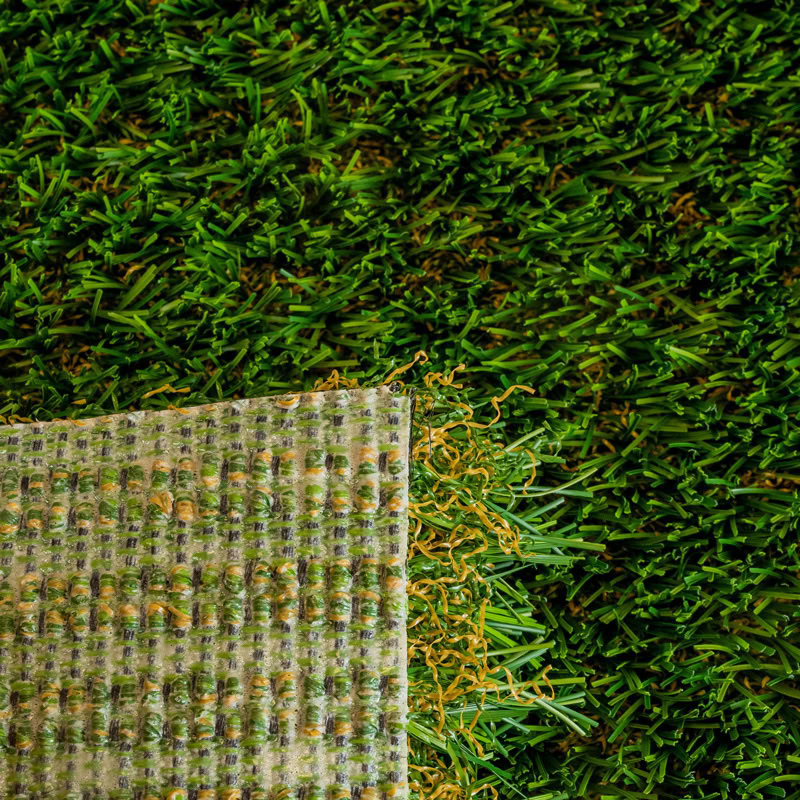 Close-up of artificial turf with natural grass in the background.