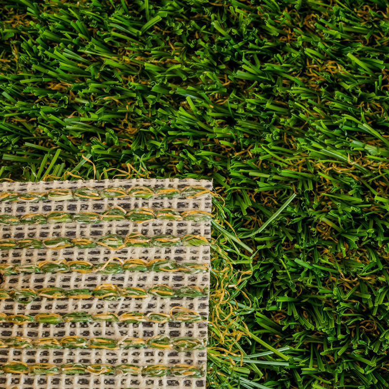 Artificial turf sample on lush green lawn for luxury landscaping.