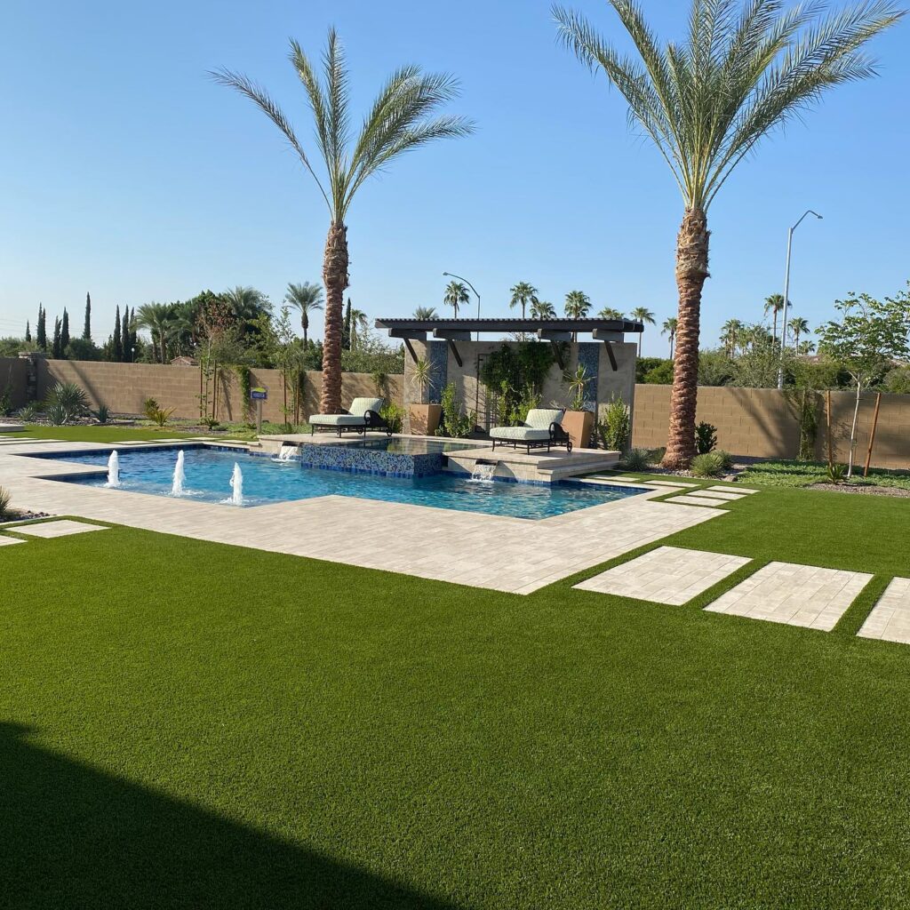 Beautiful backyard with lush green lawn, palm trees, and a swimming pool.