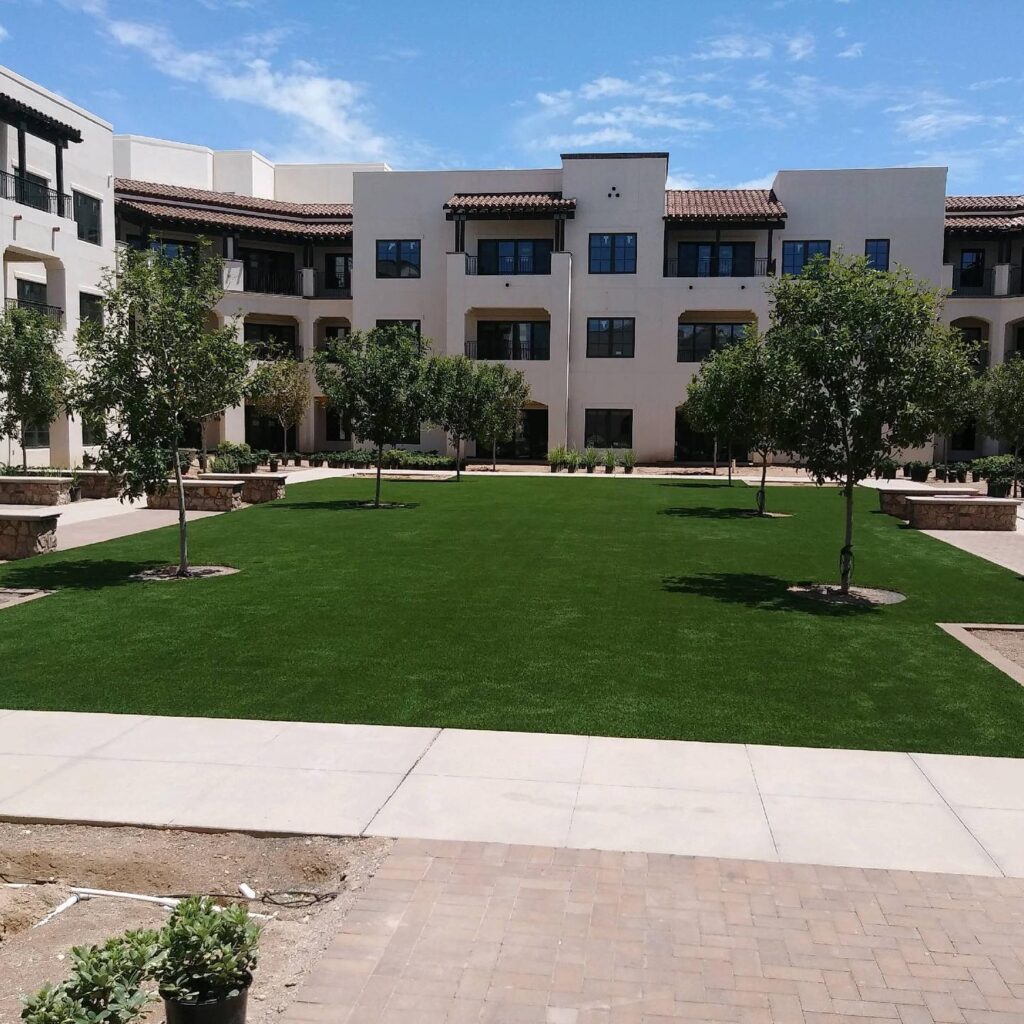 Beautiful landscaped lawn with trees and apartment buildings in Arizona.
