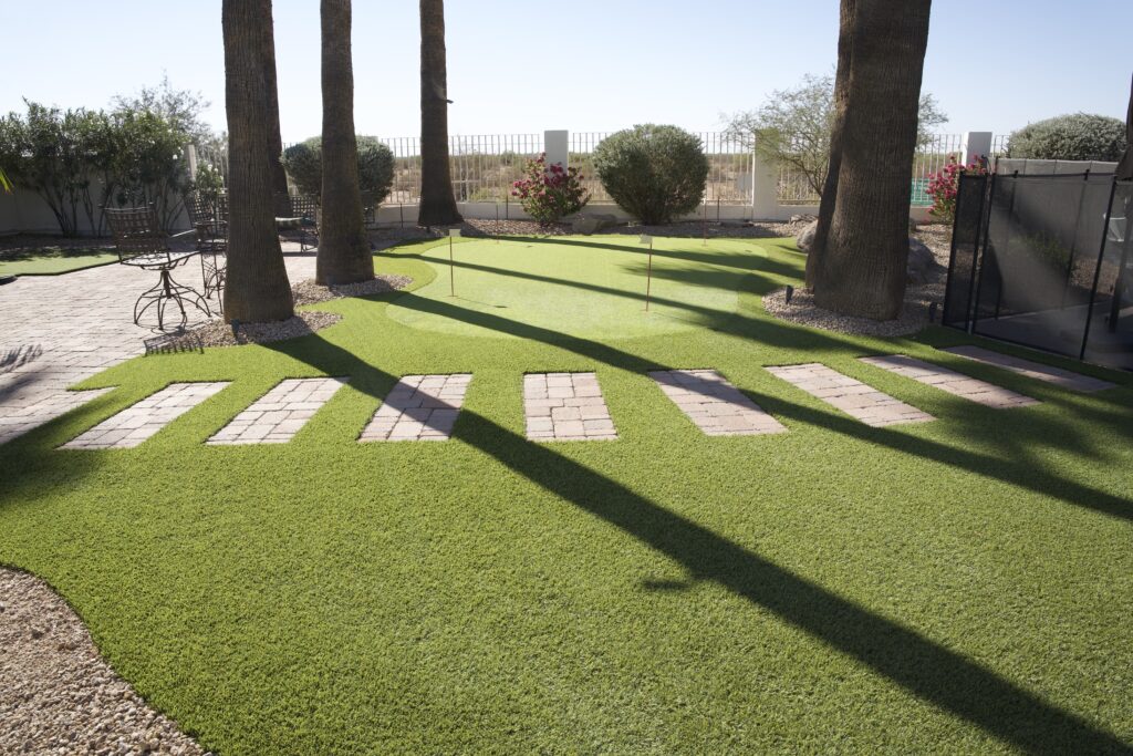 Custom backyard putting green with stepping stone walkway, artificial turf lawn, and palm trees in Arizona